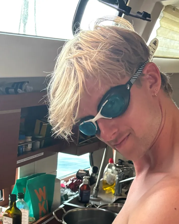 Martijn Koopman met zwembril op, in een kombuis, terwijl hij tomaten snijdt
